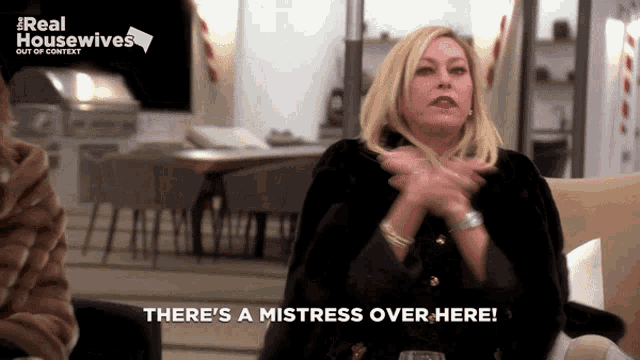 a woman sitting on a couch with the words there 's a mistress over here behind her