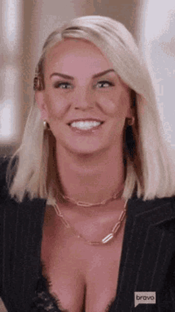 a woman wearing a black jacket and a plunging neckline is smiling