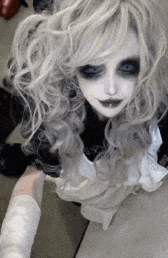 a woman with white hair and black eye makeup is wearing a white apron