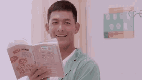 a man is laughing while reading a book in a room .