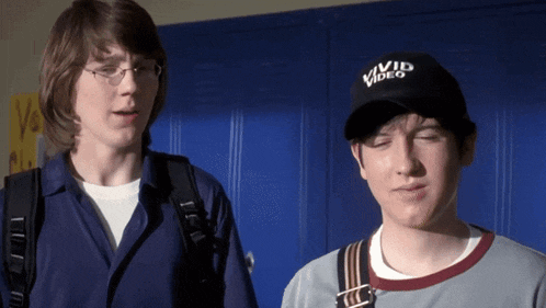 a man wearing a vivid video hat stands next to another man with his eyes closed