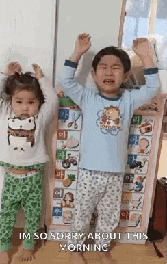 a boy and a girl are standing next to each other with their arms in the air in front of a board .