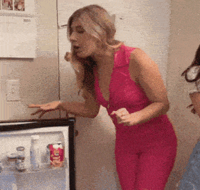 a woman in a pink dress is standing in front of a fridge with a calendar on the wall behind her that says 2023
