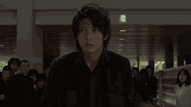 a man in a black shirt stands in front of a group of people