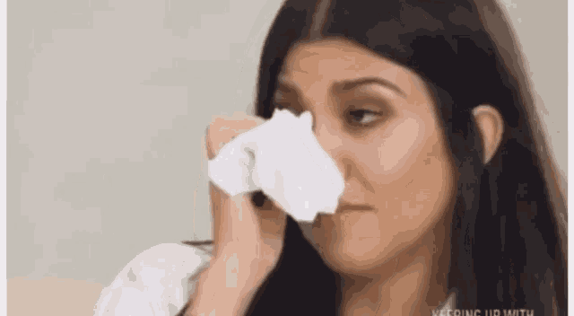 a woman is crying and holding a napkin to her face .