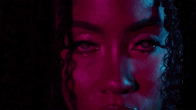 a close up of a woman 's face with purple and blue lights