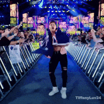 a man holding an australian flag walks down a blue aisle surrounded by fans