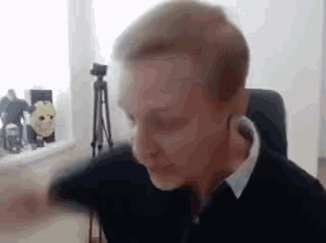 a man is sitting in a chair with his arm outstretched and a camera in the background .