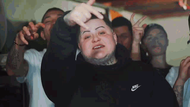 a man wearing a black nike sweatshirt is standing in front of a group of men .