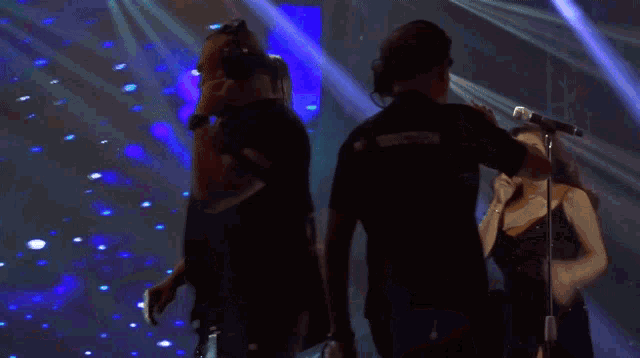 a group of people dancing in a dark room with blue lights