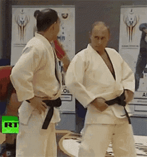 a man in a white karate uniform with a black belt is standing next to another man in a white karate uniform .