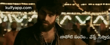 a man with a beard and necklaces is standing in front of a crowd of people .