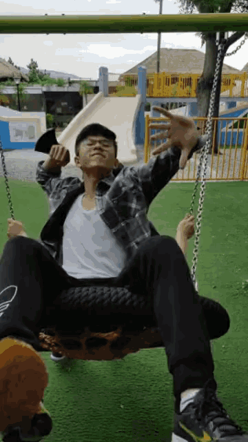 a man sits on a tire swing in a park