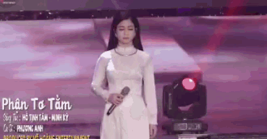 a woman in a white dress singing into a microphone