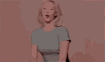 a woman is dancing in front of a pink wall in a blurry photo .