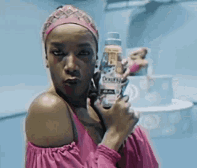 a woman in a pink dress is holding a bottle of downy
