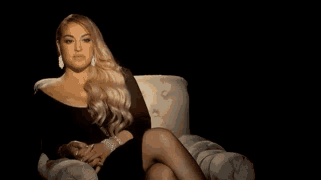 a woman is sitting on a couch with her legs crossed and looking at the camera .