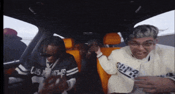 a man wearing a los angeles jersey is sitting in the back seat of a car with another man