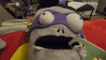a stuffed animal with a purple mask and the number 1 on the bottom right