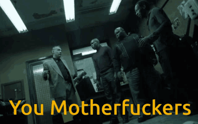 a group of men standing in a dark room with the words " you motherfuckers " written in yellow
