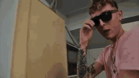 a young man in a pink shirt is standing in a room in front of a door .