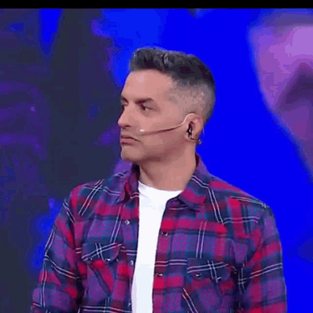 a man wearing a plaid shirt and a white shirt is making a face with his eyes closed