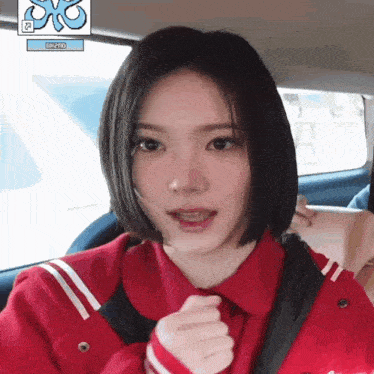 a woman in a red jacket is sitting in a car .