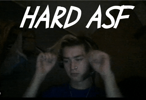 a man adjusts his ear buds in front of a hard asf sign