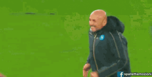 a man wearing a jacket with the letter s on it is walking on a soccer field