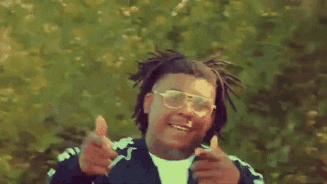 a young man wearing glasses is giving a thumbs up sign .