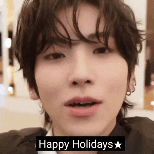 a close up of a young man 's face with the words happy holidays written below him