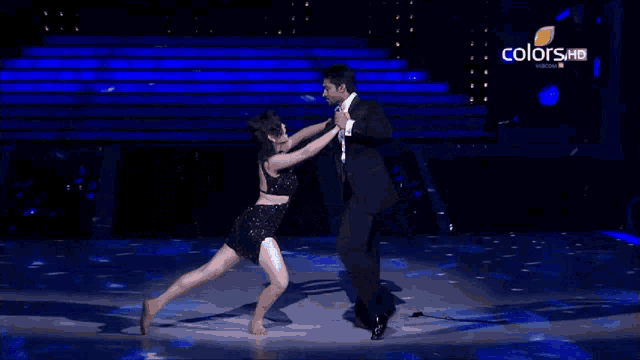 a man and a woman are dancing on a stage with the words colors hd on the bottom