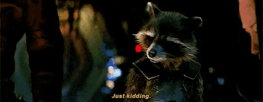 rocket raccoon from guardians of the galaxy is standing in the dark and talking to a person .