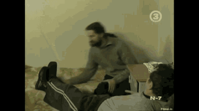 two men are laying on a bed and one of them has the number 3 on it