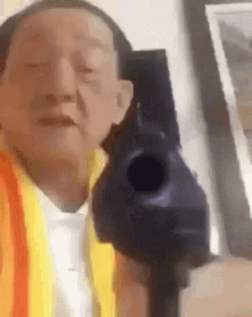 a man in a yellow vest is holding a gun in his hand .