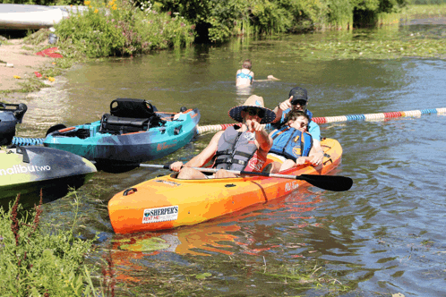a man in an orange kayak with the word malibu on the front