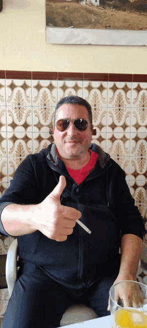 a man wearing sunglasses is giving a thumbs up sign