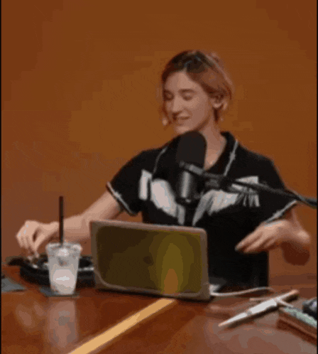 a woman is sitting at a table with a laptop and microphone .