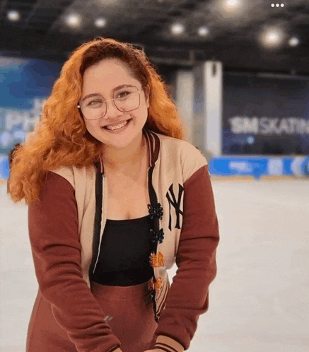 a woman wearing a ny yankees jacket is smiling