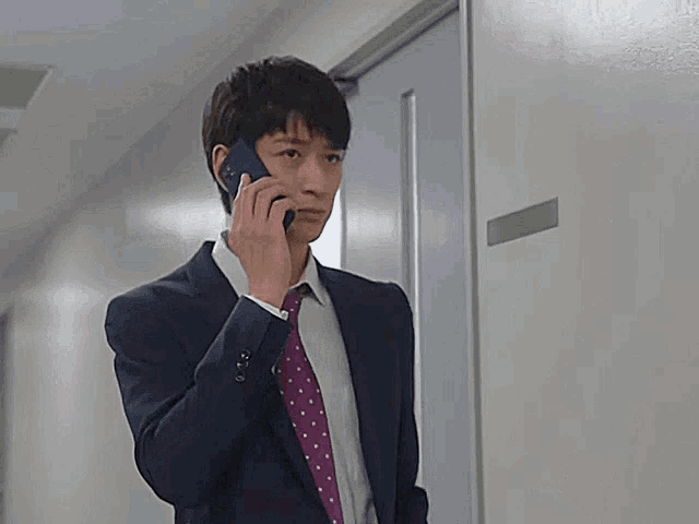 a man in a suit and tie is talking on his cell phone