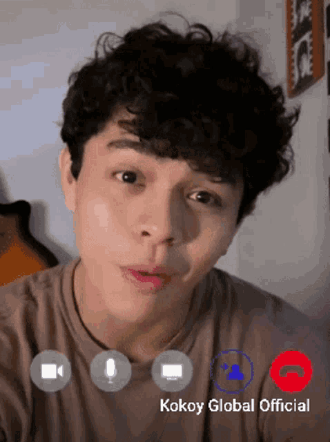 a man with curly hair is on a video call with the kokoy global official