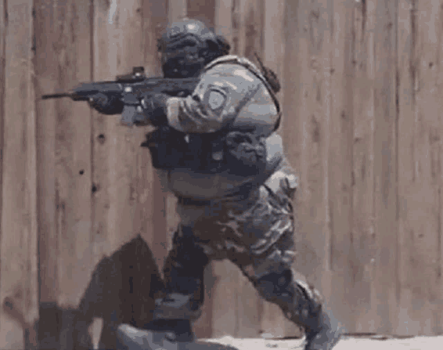a soldier is running with a gun in his hand .