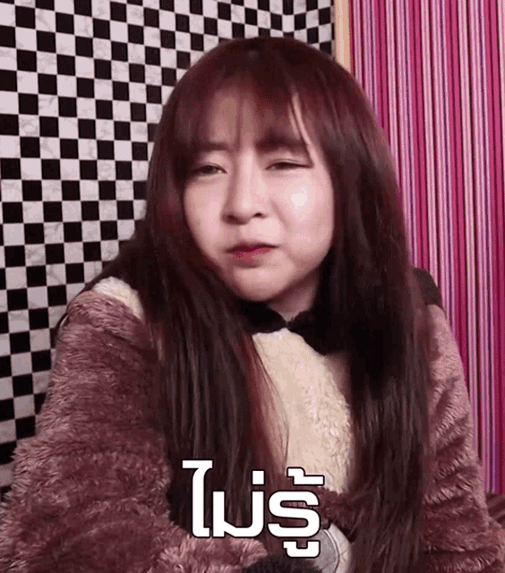a girl is making a funny face in front of a checkered curtain