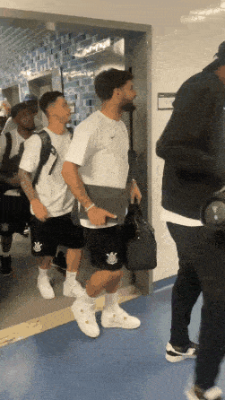 a group of men are walking down a hallway and one of them has a nike logo on his shorts