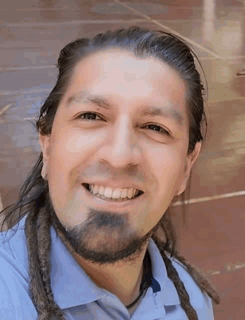 a man with dreadlocks and a beard is smiling for a picture .