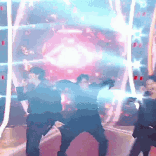 a group of people are dancing on a stage with a pink light behind them .