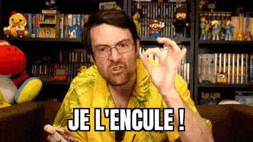 a man wearing glasses and a yellow shirt is holding a video game controller and saying `` je l ' encule '' .