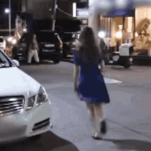 a woman in a blue dress is walking down a city street .