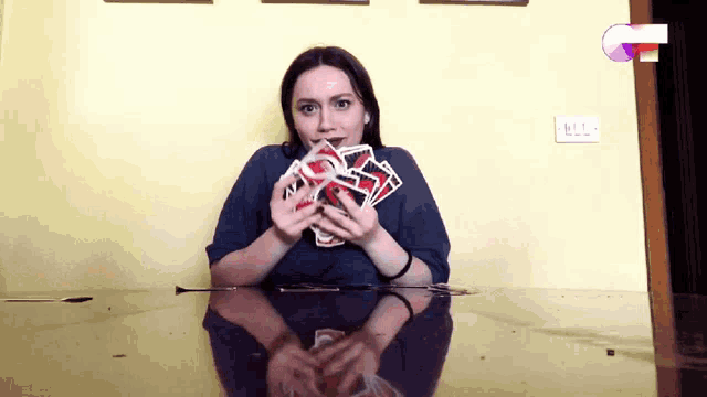 a woman sitting at a table with a bunch of playing cards in her hand