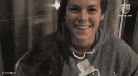 a woman is smiling while sitting in a chair and wearing a sweatshirt .
